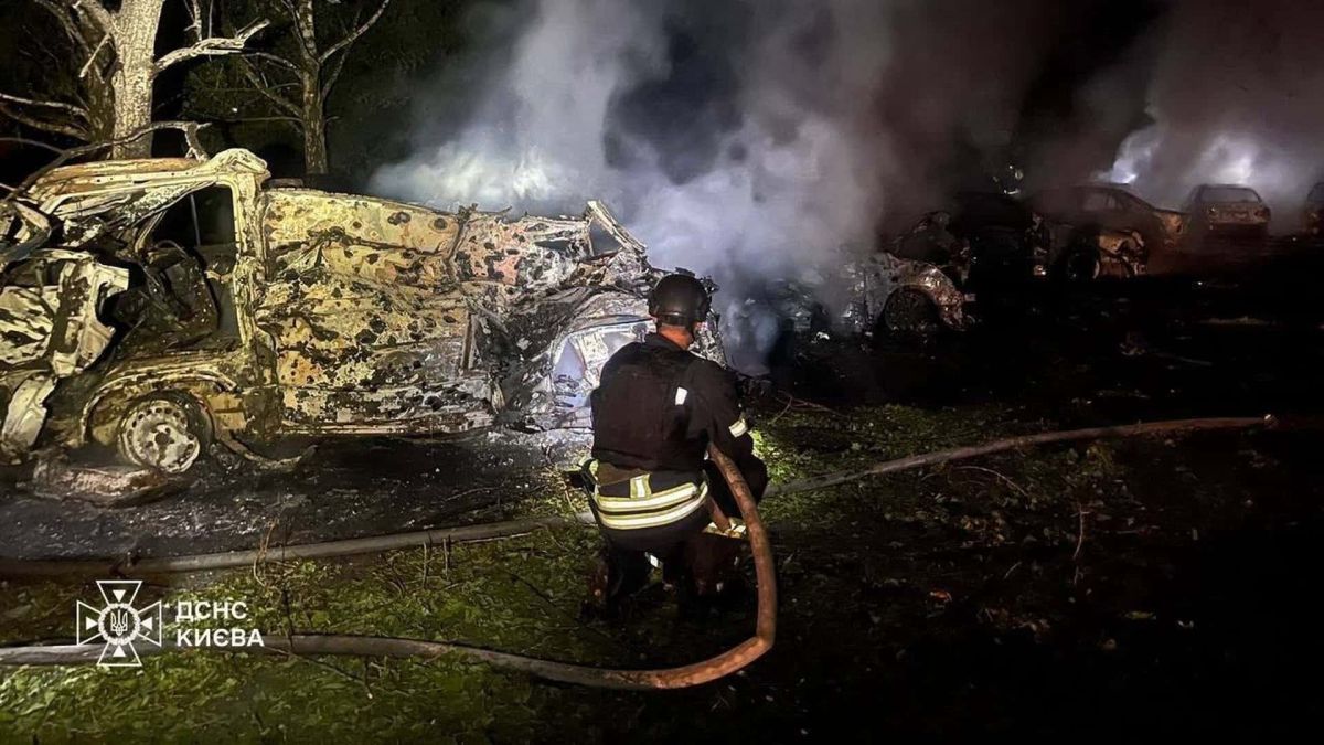 Рятувальник ДСНС гасить згорілі автомобілі вночі після балістичного удару по Києву