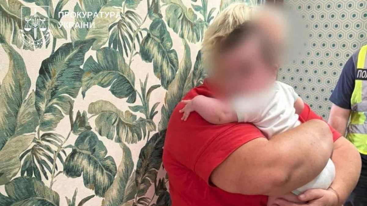 Маленька дитина на руках у жінки в червоній футболці