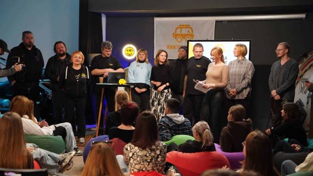 Команда викладачів стоять перед дітьми в приміщенні творчої студії