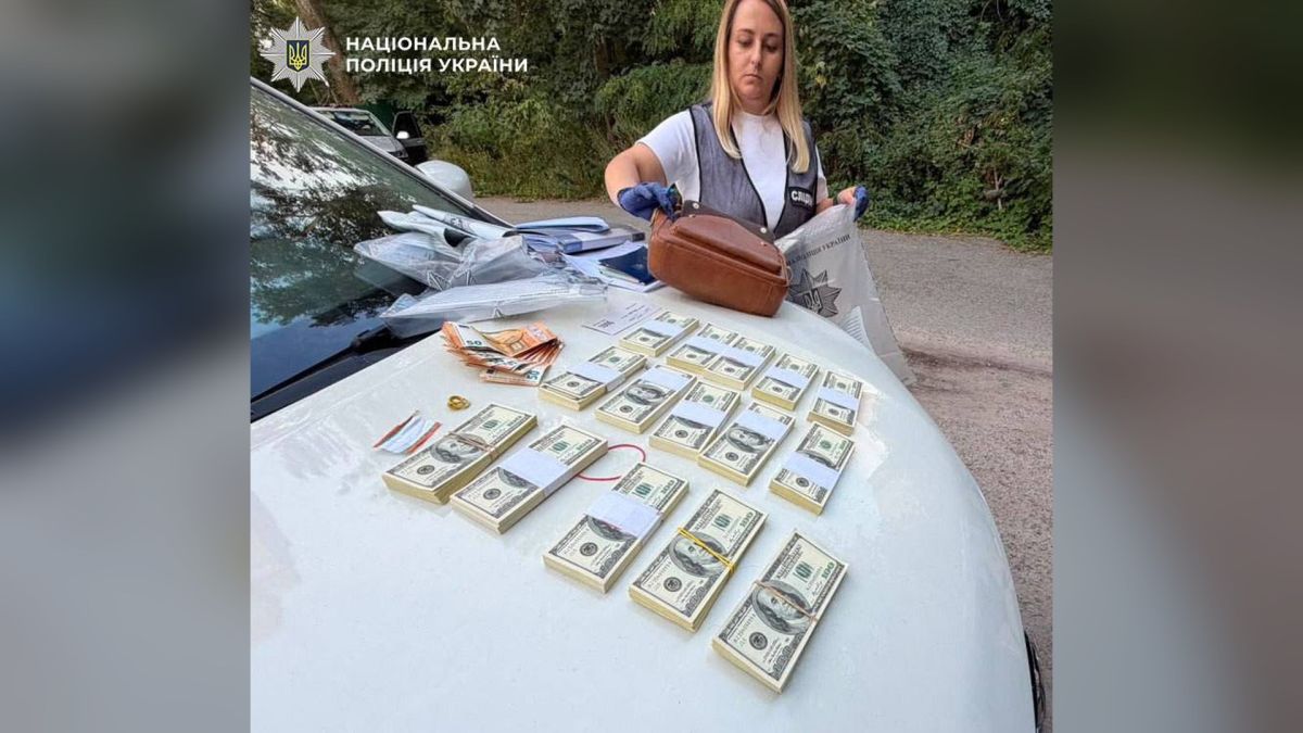 Двох адвокатів підозрюють у шахрайстві з виробником дронів на 55 тисяч євро Слідча поліції біля автомобіля, на капоті якого розкладено пачки доларів і євро, вилучені під час затримання двох адвокатів у Києві