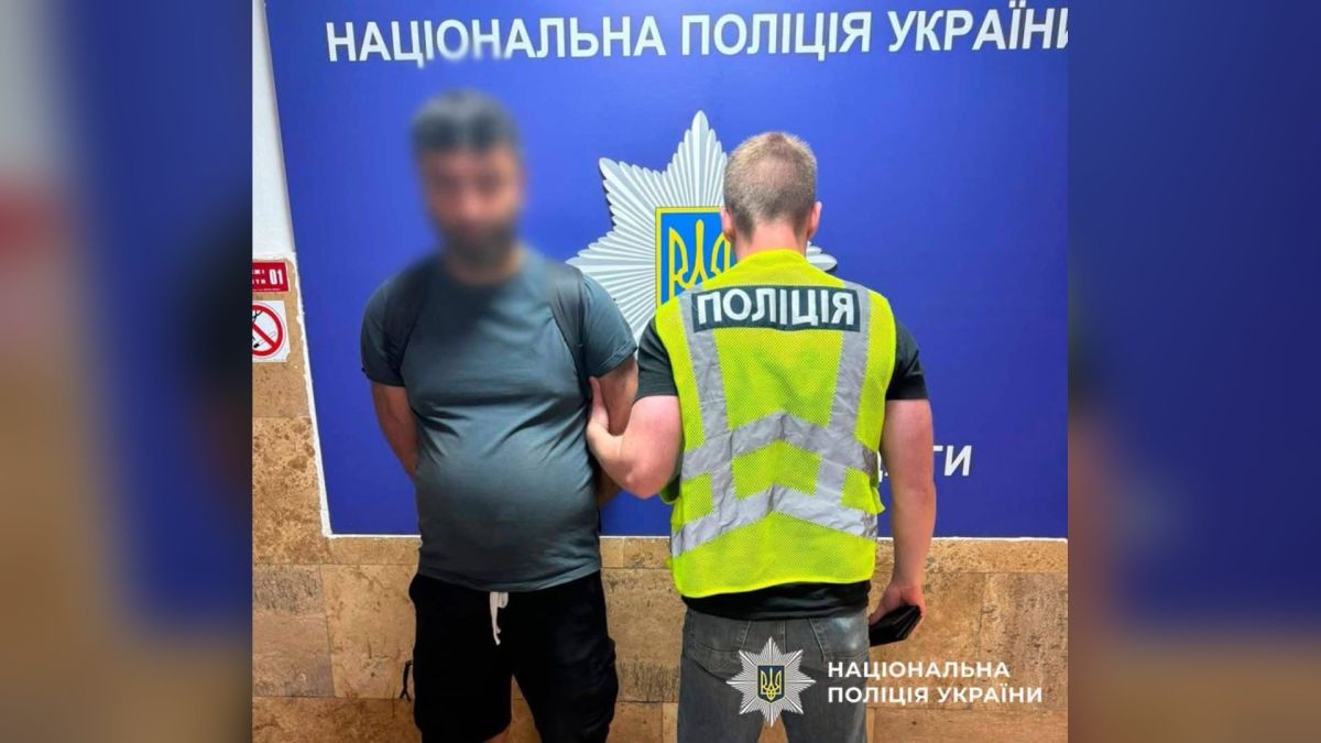До суду скерували справу 35-річного іноземця за грабіж у парку «Нивки» Поліцейський у світловідбивному жилеті тримає за руку чоловіка з розмитим обличчям на тлі синього стенда Національної поліції України