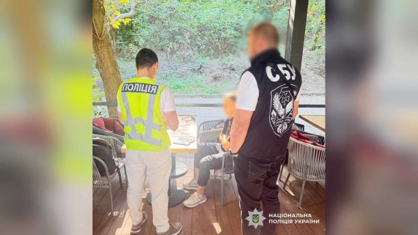 Двох кур’єрів шахраїв судитимуть за схему з «перевіркою СБУ» на 2,8 млн Поліцейський і співробітник СБУ біля затриманого чоловіка за столиком літнього майданчика кафе в Києві
