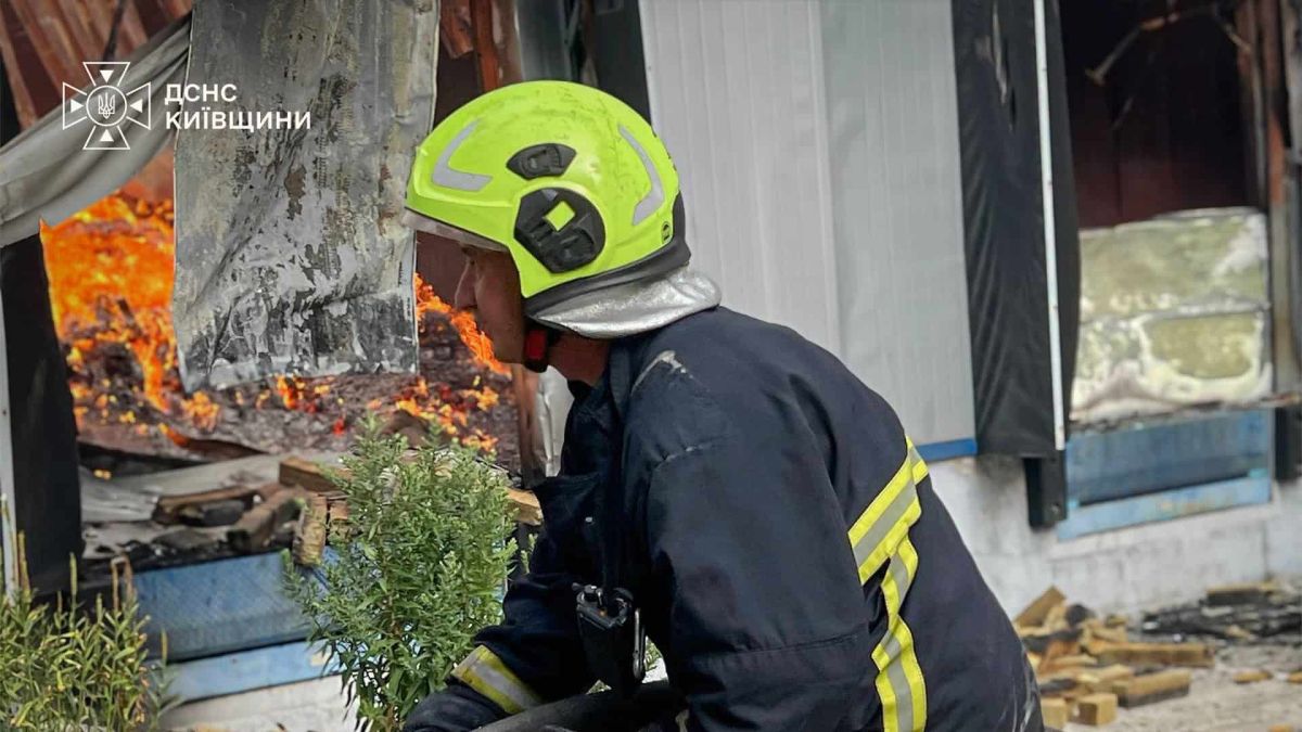 Дрони атакували три райони Київщини, загинув один, поранено двох Рятувальник ДСНС у захисному шоломі тримає пожежний рукав на тлі яскравого полум'я, що виривається з пошкодженої будівлі