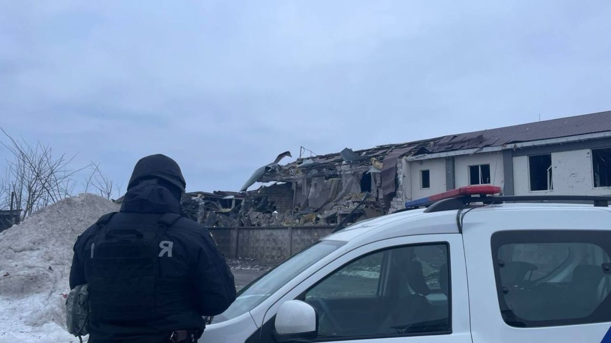 Атака на Київщину: пошкоджено 8 будинків у чотирьох районах Поліцейський у чорній формі оглядає зруйнований будинок після атаки на Київщину, поруч патрульне авто