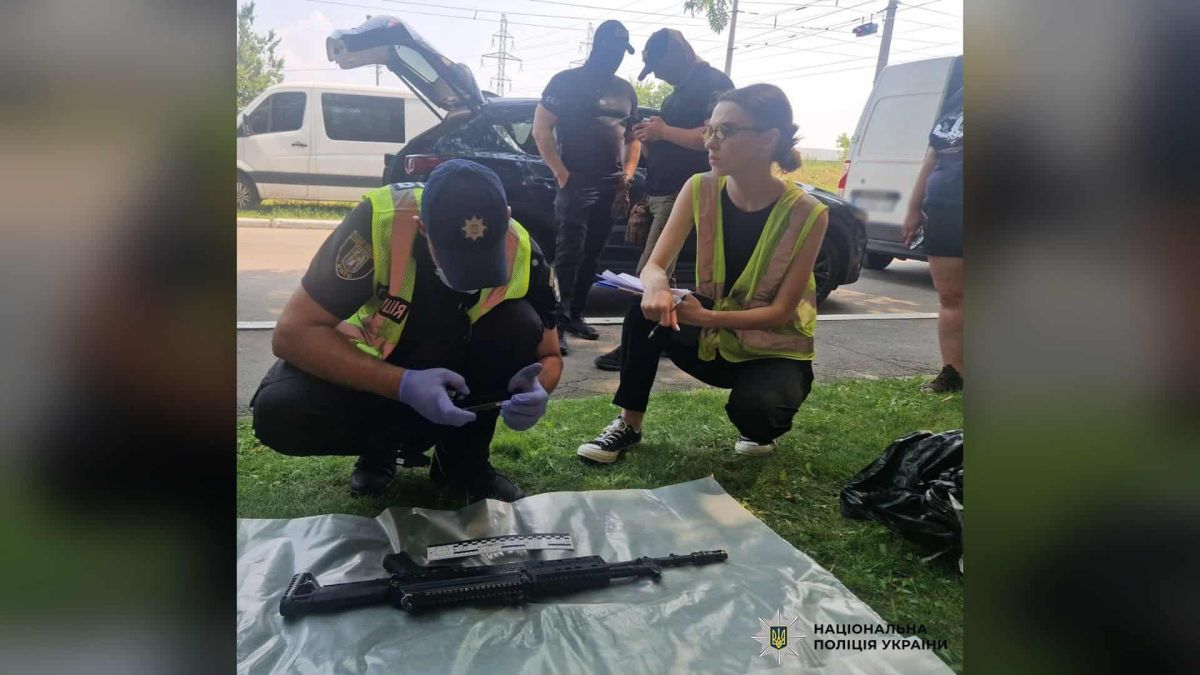 Поліцейський і слідча оглядають вилучений автомат на плівці під час слідчих дій у справі про продаж трофейної зброї в Києві