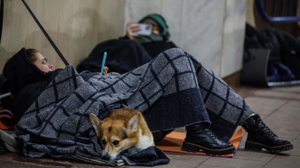 Жінка з домашнім улюбленцем на підлозі станції метро під час тривоги