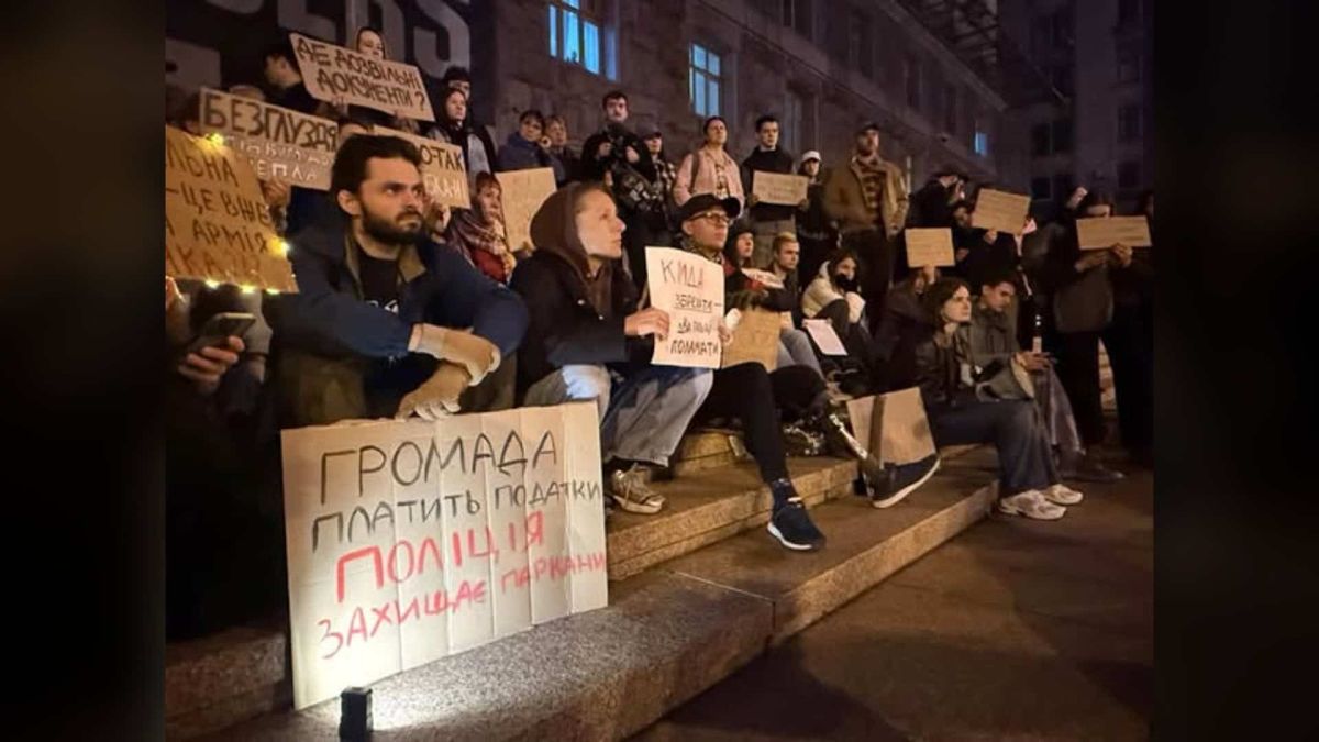 Біля КМДА одночасно протестували проти вирубки і за теплотрасу Учасники протесту сидять на сходах біля КМДА з плакатами проти вирубки дерев на Теремках увечері