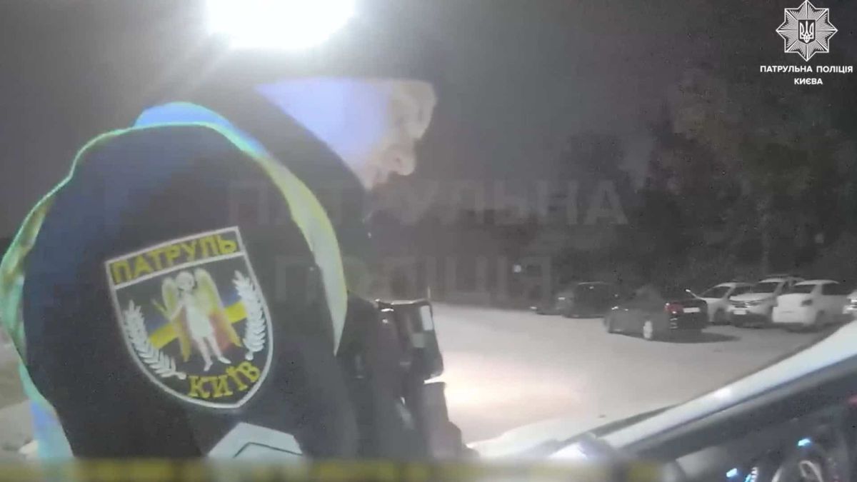 Скриншот з відео з бодікамер поліції, чоловік поліцейський стоїть біля машини в темряві