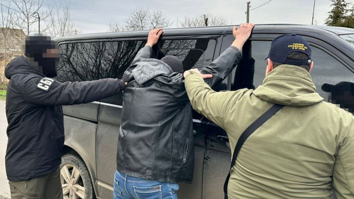 Працівники СБУ і затриманий підозрюваний біля автомобіля
