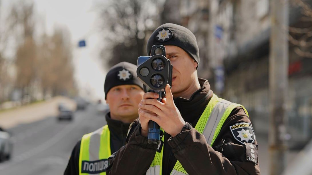 Поліцейський тримає радар для вимірювання швидкості автомобілів