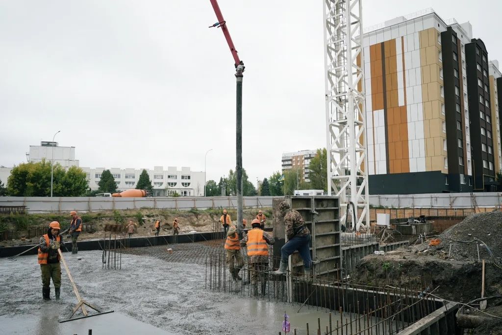 Будівельники заливають бетонний фундамент нового житлового будинку