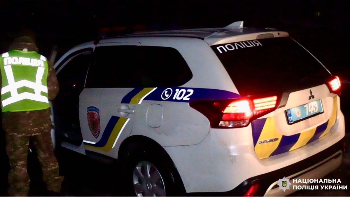 Поліцейський НПУ відкриває двері патрульного автомобіля