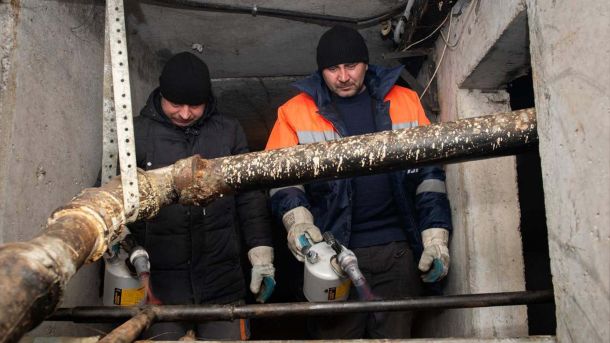 Двоє працівників комунальної служби розігрівають трубу невеликого діаметру