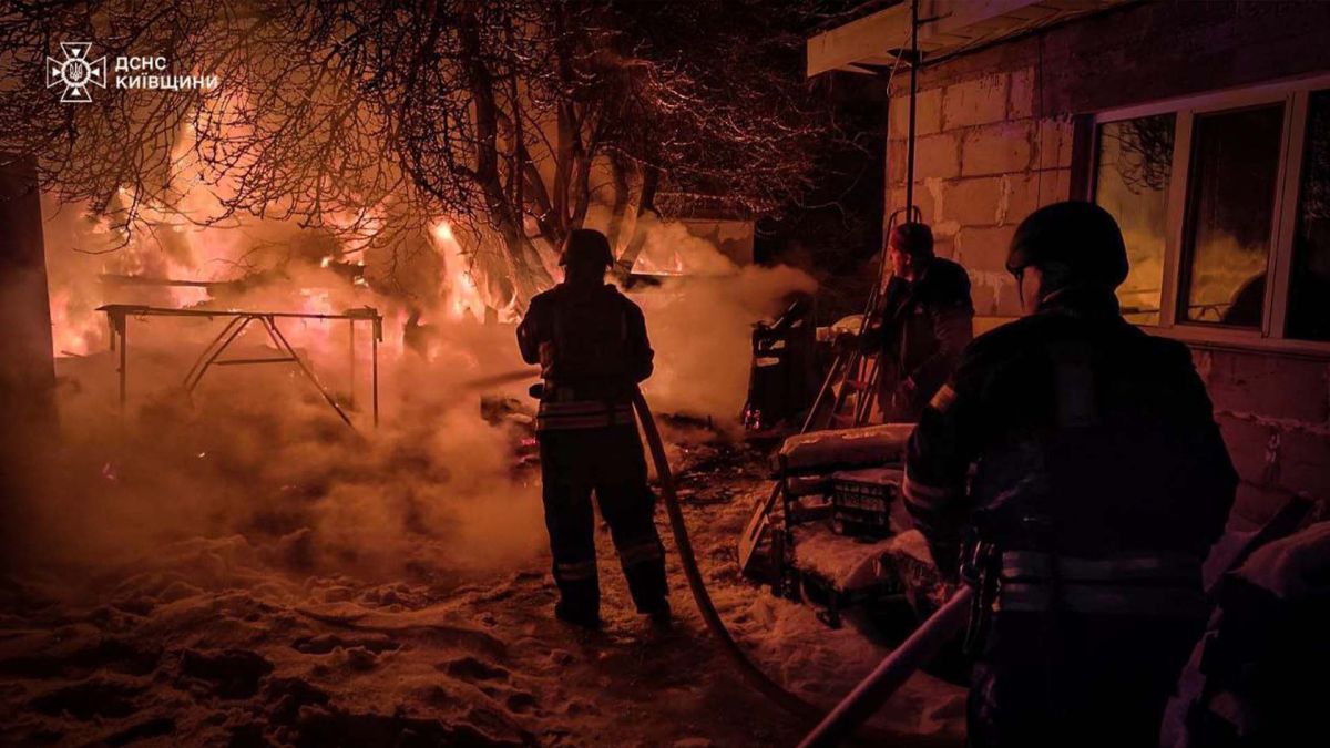 Троє пожежників під час гасіння пожежі в темну пору доби