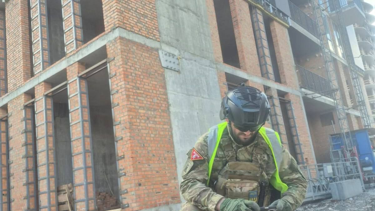 Співробітник НПУ у захисному спорядженні оглядає уламки ворожого безпілотника біля зруйнованої будівлі в Києві після денної атаки дронів 28 квітня 2026 року