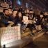 Головні новини Києва | Kyiv.News Учасники протесту сидять на сходах біля КМДА з плакатами проти вирубки дерев на Теремках увечері