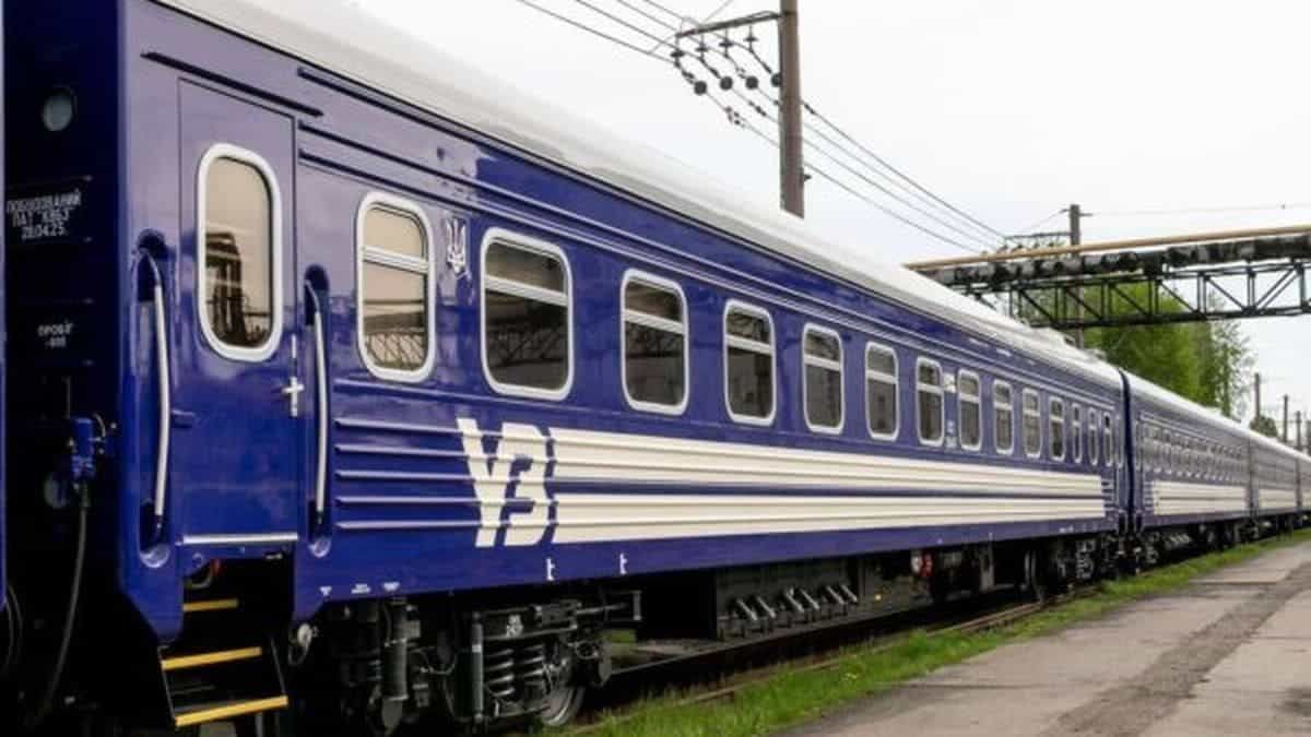 Синій пасажирський вагон «Укрзалізниці», що стоїть на залізничній колії