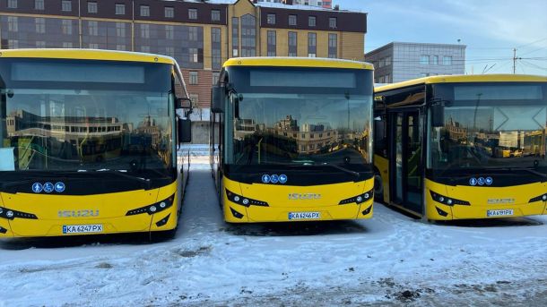 У Києві з 5 до 8 березня обмежать рух мостами та шляхопроводами Три жовті автобуси ISUZU Київпастрансу з київськими номерними знаками на засніженій стоянці на тлі житлових будинків