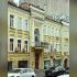 Сучасний вигляд триповерхового будинку на Прорізній, 22А у Києві: жовтий фасад, балкон із двоколонним портиком і арковий вхід