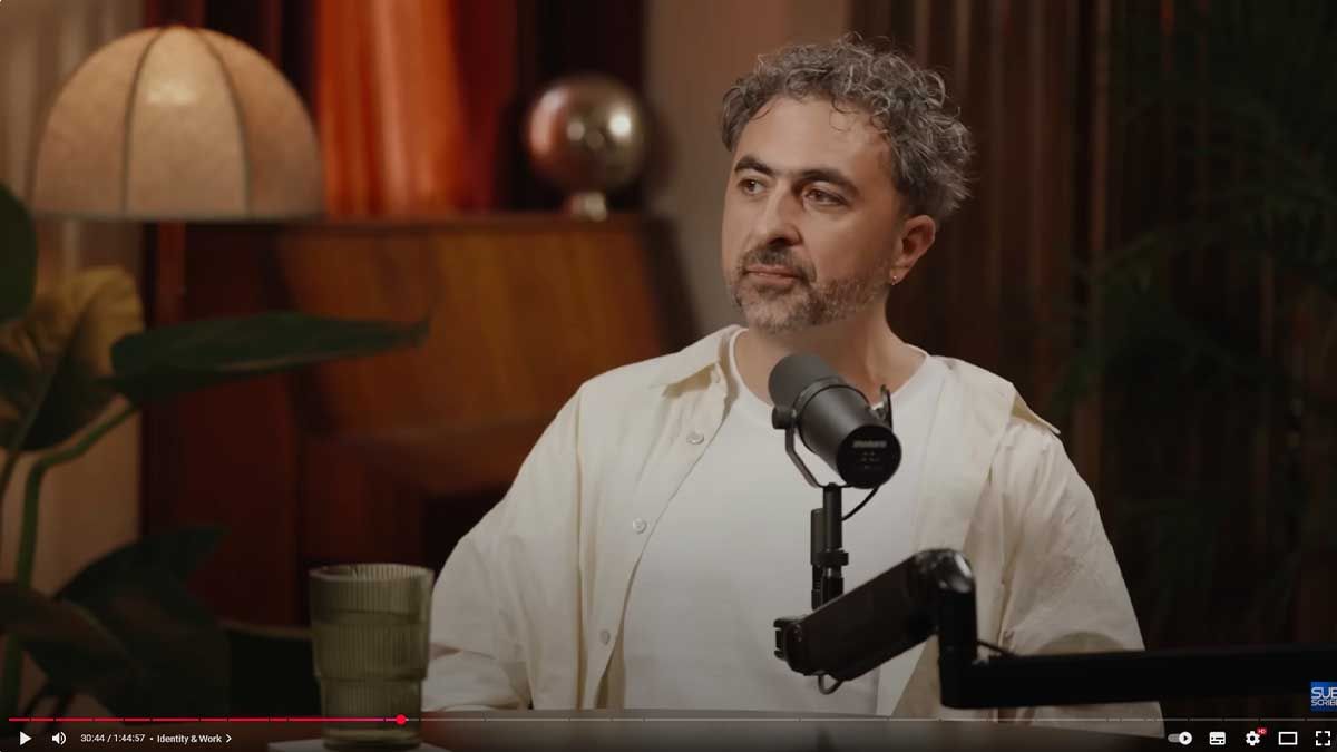 Мустафа Сулейман одягнений в білу сорочку біля студійного мікрофону