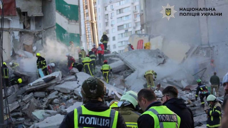 Поліцейські в жовтих жилетах і рятувальники в касках розбирають завали зруйнованого багатоповерхового будинку в Дарницькому районі Києва після масованої ракетної атаки 14 травня 2026 року