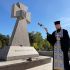 Головні новини Києва | Kyiv.News Священник із кадилом і хрестом біля кам’яного козацького хреста з написом «Героям слава» на кладовищі, квіти на постаменті