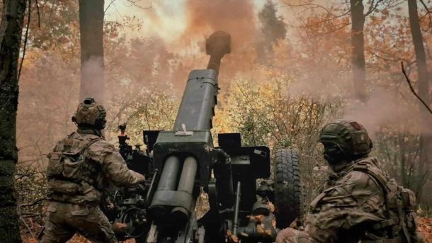 Двоє військових видять біля гармати в осінній лісопосадці і стріляють з неї