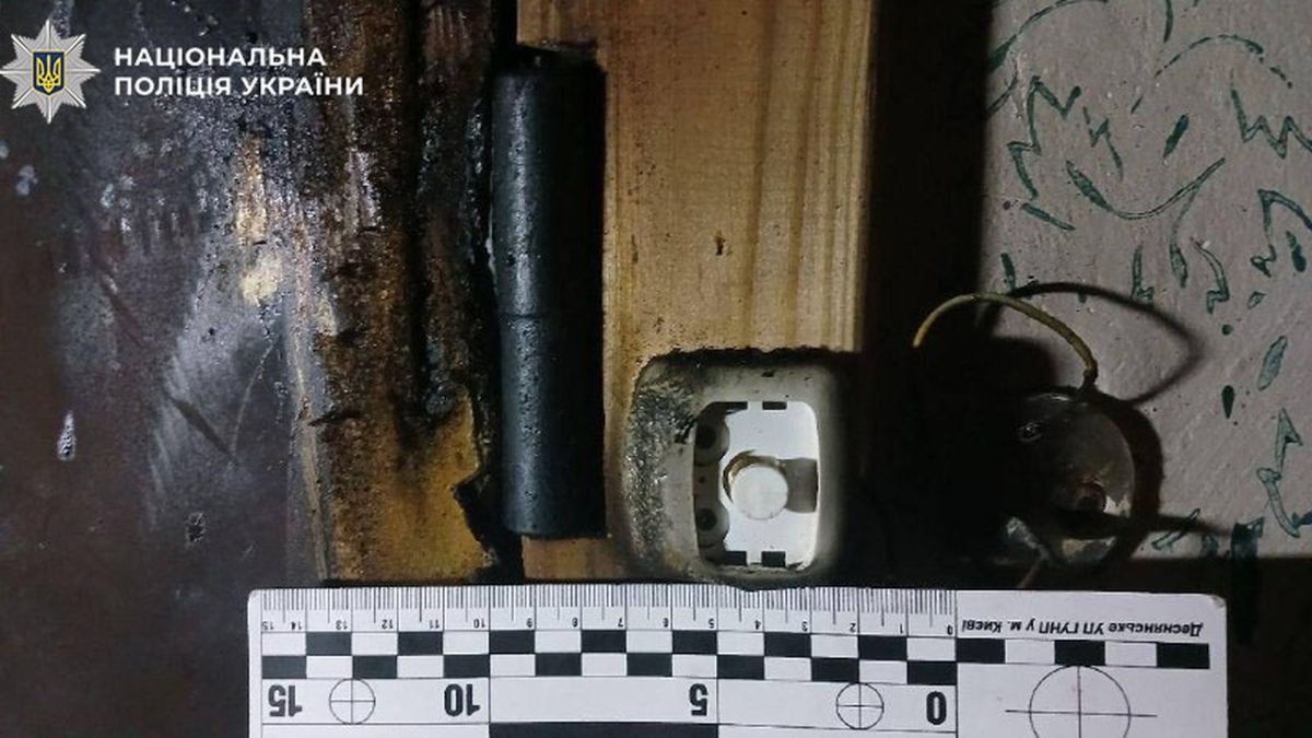 Обгорілий край вхідних дверей квартири з оплавленою розеткою та лінійкою слідчих у Деснянському р-ні Києва