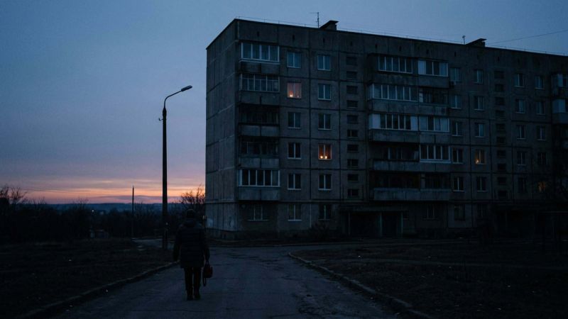 Житловий будинок у сутінках без світла, лише кілька вікон освітлені свічками