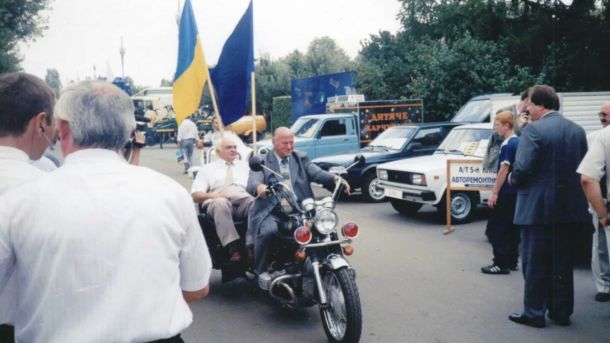 Ретро мотоцикли їдуть по вулиці, за кермом дідусь