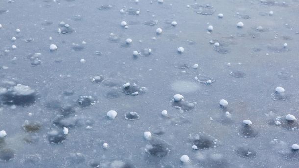 Замерзла поверхня води з кульками граду та крижаними бульбашками — ожеледиця на дорогах Київщини