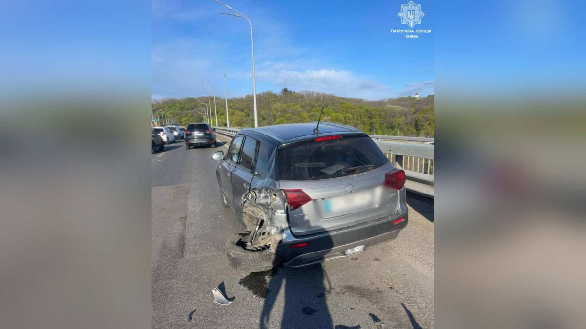 Пошкоджений Suzuki з відірваним заднім колесом після ДТП на Дарницькому мосту в Києві, поруч проїжджають інші автомобілі