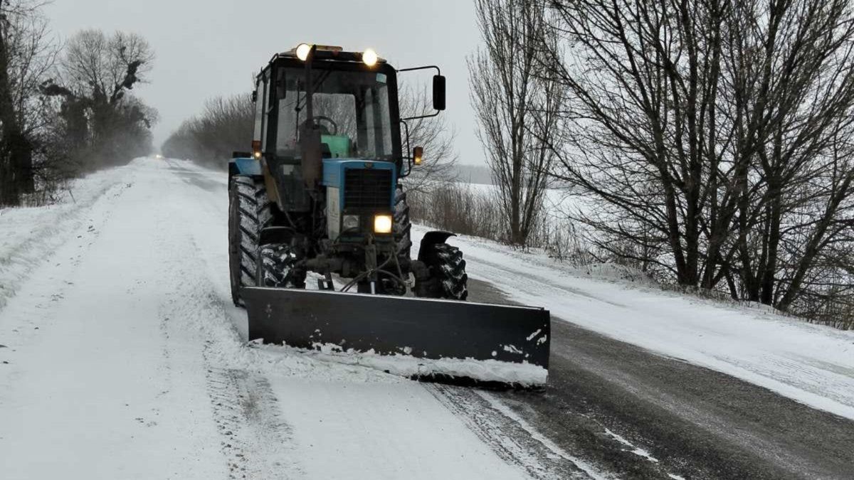 Трактор із відвалом розчищає засніжену дорогу на Київщині, робота комунальних служб під час снігопаду