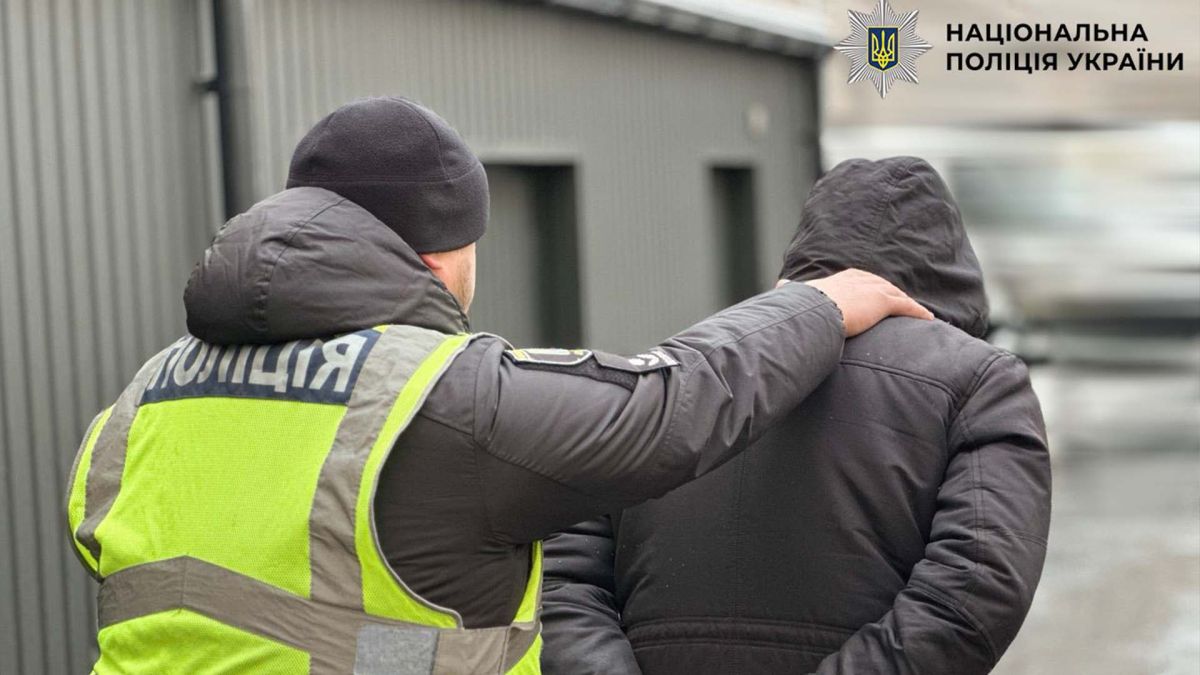 Поліцейський у жовтому жилеті конвоює затриманого підозрюваного у збуті наркотиків у Києві