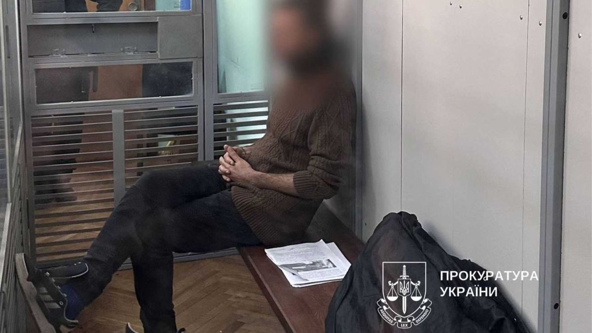Підозрюваний у кросівках без шнурків сидить в камері за склом в судовій залі