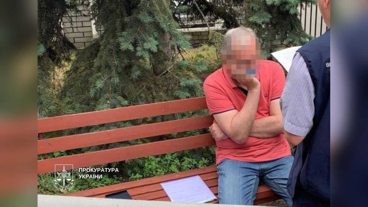 Апеляційний суд залишив адвокату 5 років за підбурення до хабаря судді Чоловік у червоній футболці сидить на лавці поруч із правоохоронцем під час затримання адвоката в Києві, фото прокуратури