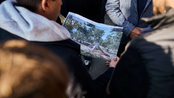Чоловік тримає в руках фотографію проєкту парка, який планують збудувати