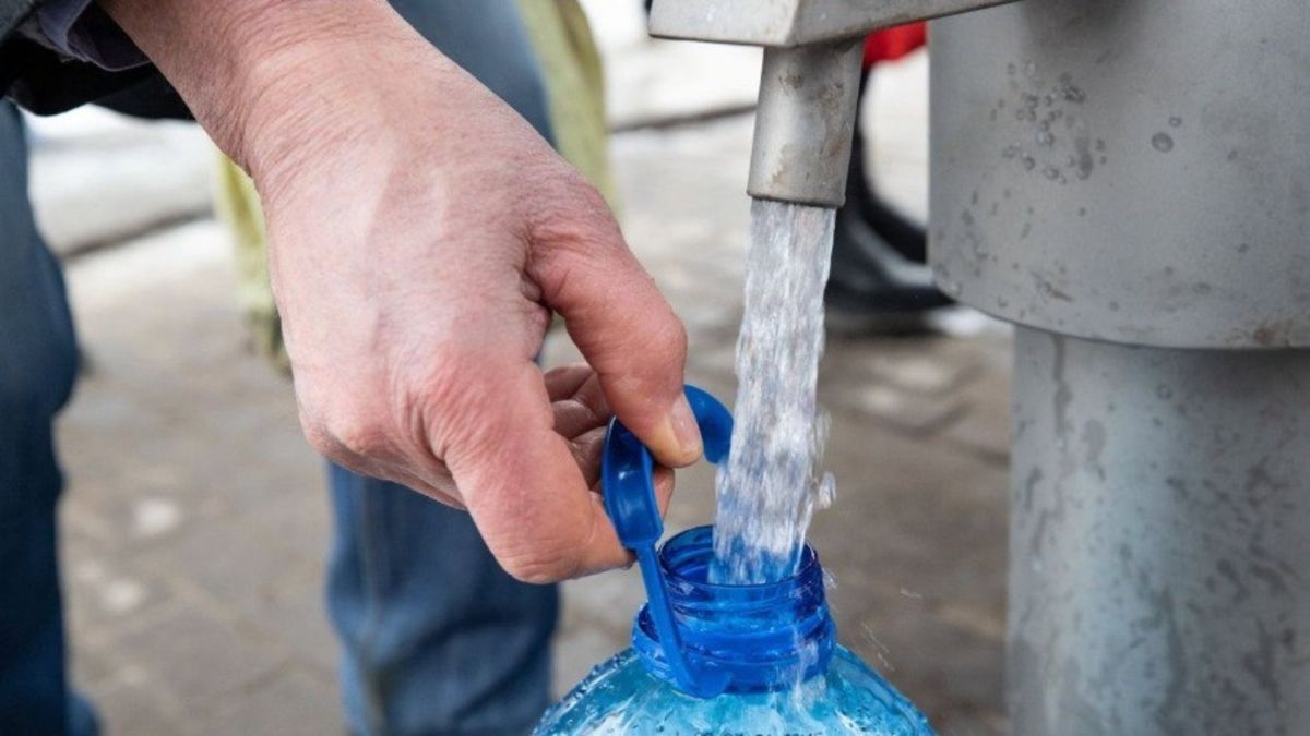 Чоловік набирає воду з артезіанської свердловини