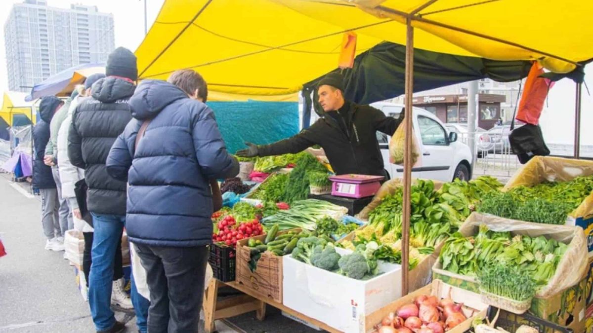 Продавець та покупці на продуктовому сільськогосподарському ярмарку в Києві — свіжі овочі та зелень просто від виробників