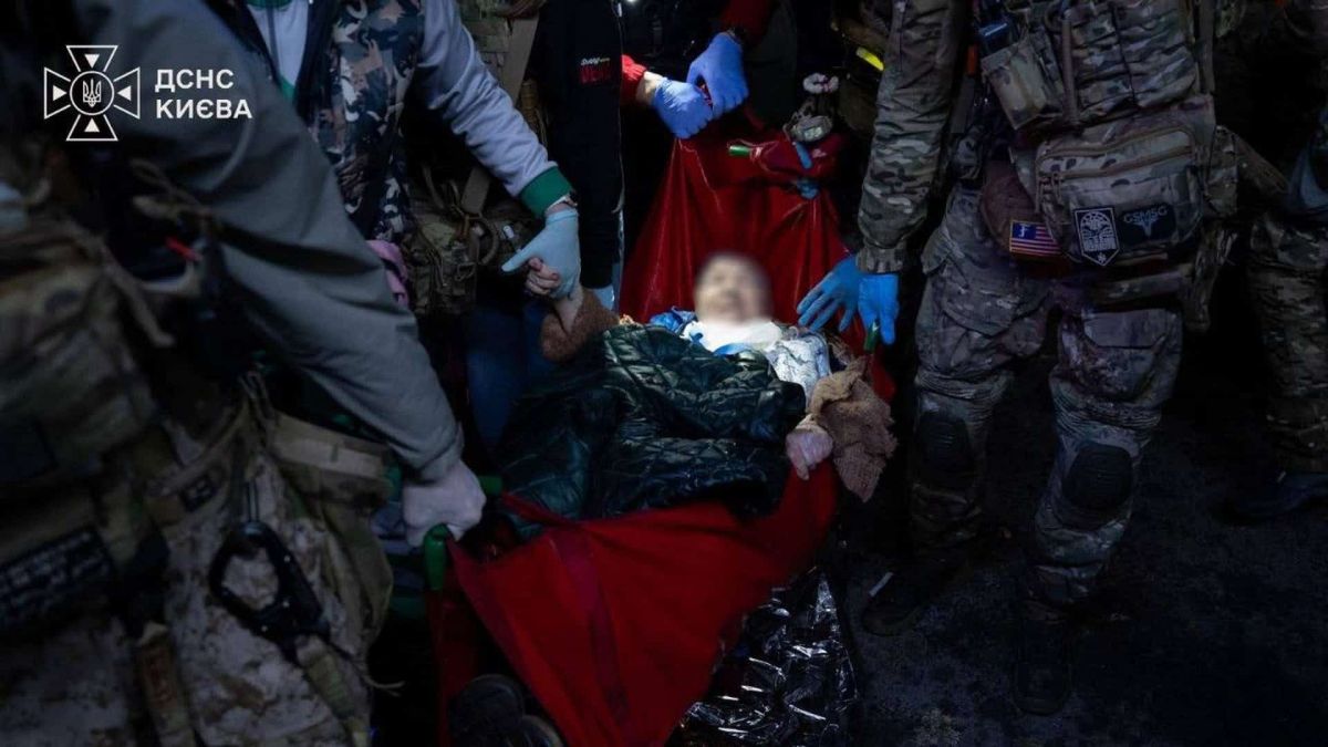 Атака на Київ: троє загиблих і 32 постраждалих, серед них дитина (оновлено) Рятувальники та медики несуть на червоних ношах постраждалу людину після нічної атаки на Деснянський р-н Києва 14 жовтня, обличчя розмите