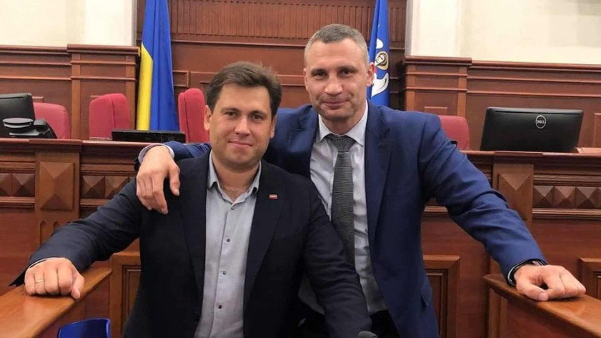 Двоє чоловіків у ділових костюмах позують у залі засідань
