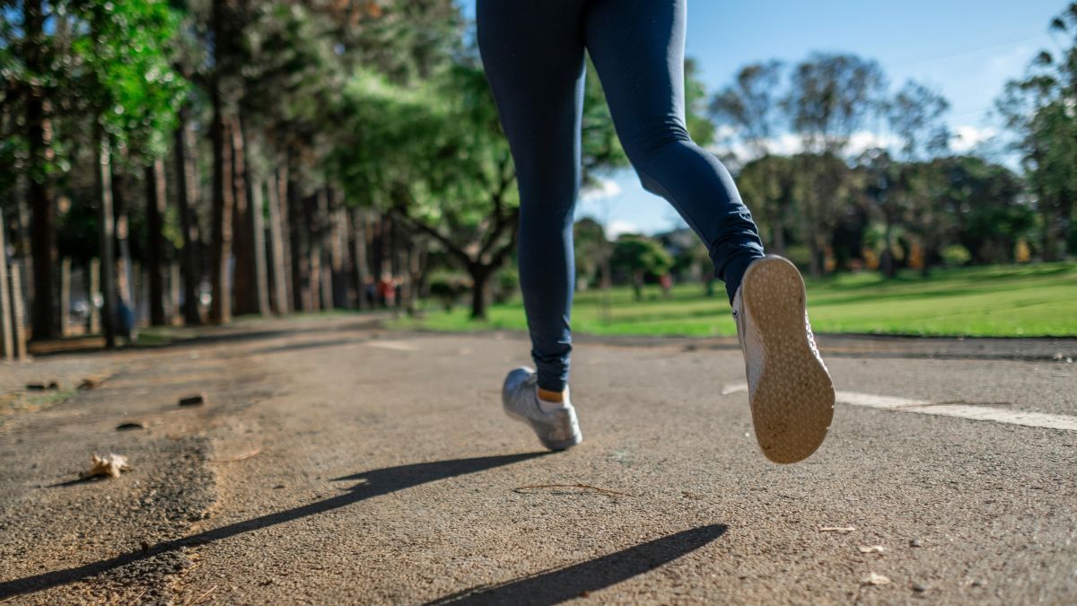 Ноги дівчини, яка біжить по парку в кросівках