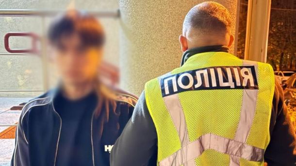 Працівник поліції тримає під руку затриманого чоловіка, його обличчя заблюрене
