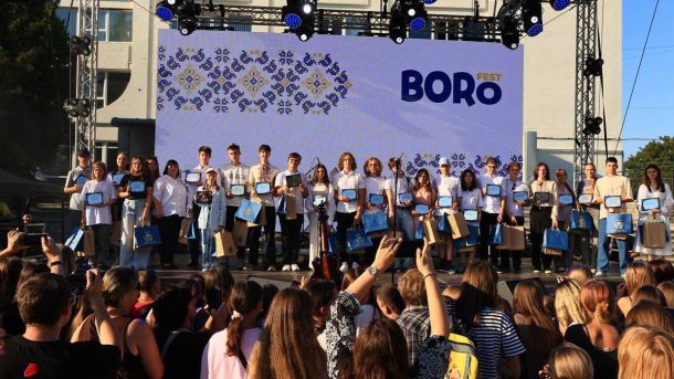 Біля сцени молоді люди отримують нагороди на фестивалі Boro Fest у Києві, з великим глядацьким залом та яскравим екраном у фоні.