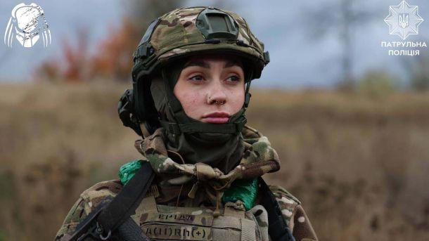 Жінка-військовослужбовець у камуфляжі та шоломі уважно дивиться вдалину