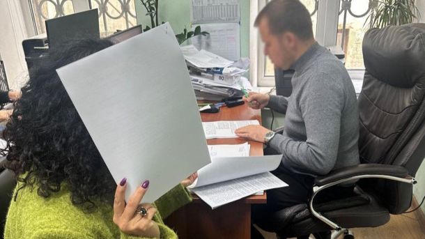 Викрали військового та вимагали 30 тисяч: групу затримали на Київщині Жінка в зеленому светрі закриває обличчя паперами, біля неї за столом сидить чоловік