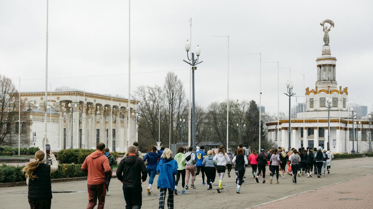 Учасники благодійного забігу «7 бігових субот» біжать алеєю ВДНГ у Києві під час першого старту 11 квітня 2026 року