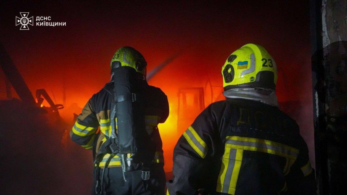 Двоє рятувальників ДСНС спрямовують воду в місце, де триває пожежа