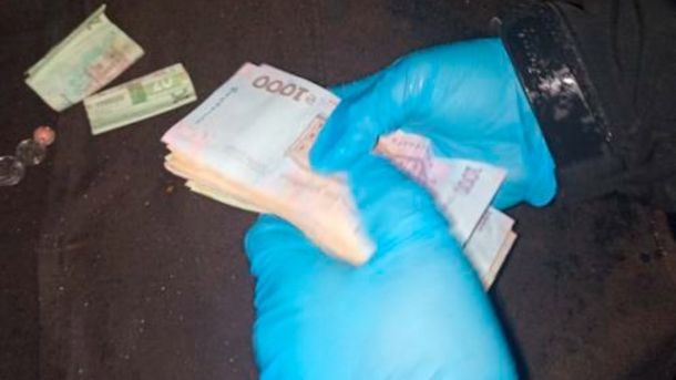 Пам'ятку на Андріївському узвозі дозволили розібрати Правоохоронець тримає в руках пачку грошових банкнот
