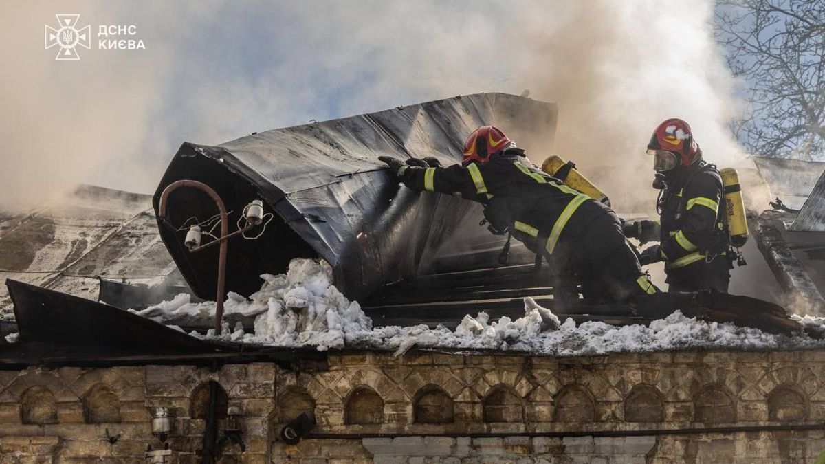 Рятувальники ДСНС у спорядженні гасять пожежу на даху житлового будинку в Голосіївському районі Києва, густий дим здіймається над пошкодженою покрівлею